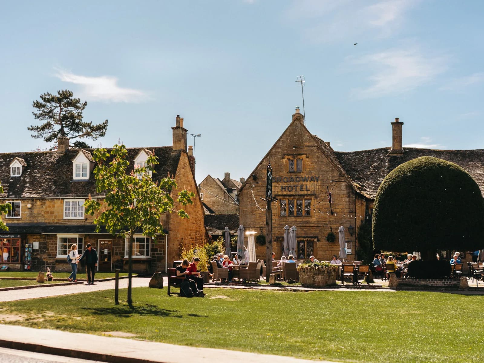 The village green outside the Broadway Hotel in Broadway, Cotswolds, with people at outdoor tables